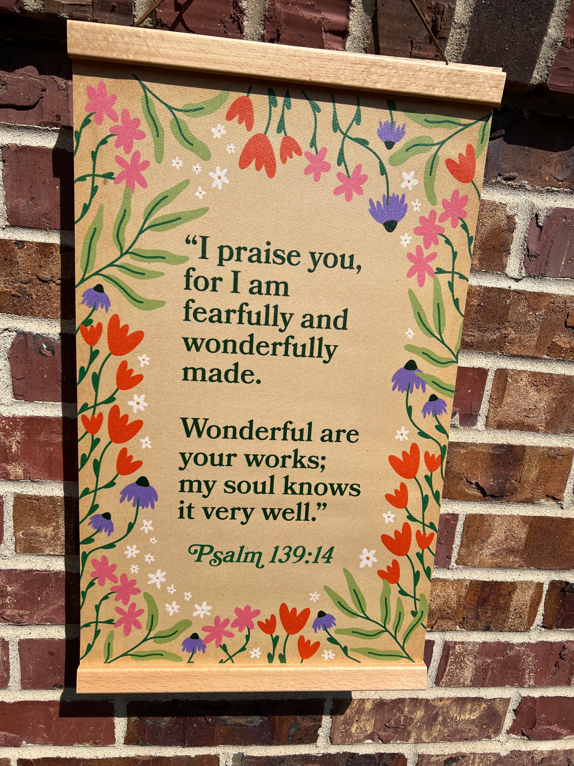 Decorative sign with floral design and Psalm 139:14 text on a brick wall background